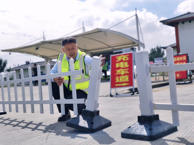 1759107300523728.jpg 為提升節假日期間通行效率,濉溪服務區在節前提前完成油電車道分離工作。圖為濉溪服務區物業安全職員王仲連在擺放隔離柵欄。.jpg